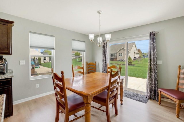 dining space featuring a healthy amount of sunlight, baseboards, light wood-style flooring, and a chandelier