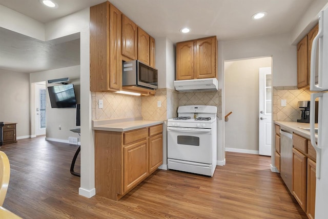 1112 Marquette Ave, Green Bay, WI 54304 - kitchen with decorative backsplash, appliances with stainless steel finishes, light countertops, light wood-style floors, and under cabinet range hood