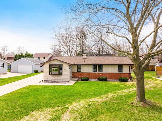 view of front facade with brick siding, a front lawn, fence, and a detached garage