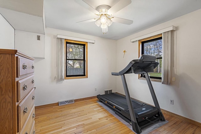 exercise room featuring visible vents, light wood finished floors, ceiling fan, and baseboards