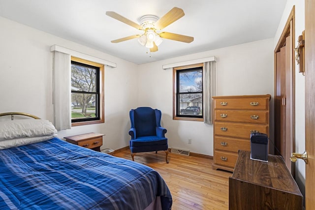bedroom featuring visible vents, a ceiling fan, light wood finished floors, and baseboards