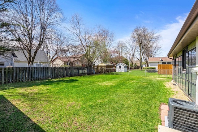 view of yard featuring an outdoor structure, cooling unit, a fenced backyard, and a shed