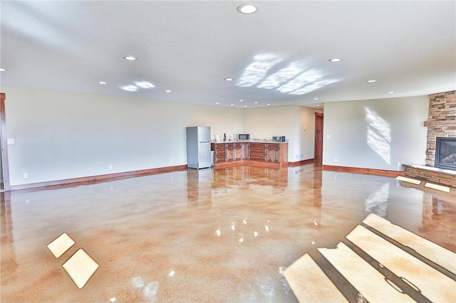 203 Walnut Hill Way, River Falls, WI 54022 - unfurnished living room featuring concrete flooring, recessed lighting, a stone fireplace, and baseboards