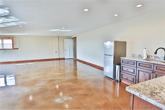 203 Walnut Hill Way, River Falls, WI 54022 - kitchen with a sink, freestanding refrigerator, baseboards, finished concrete flooring, and recessed lighting