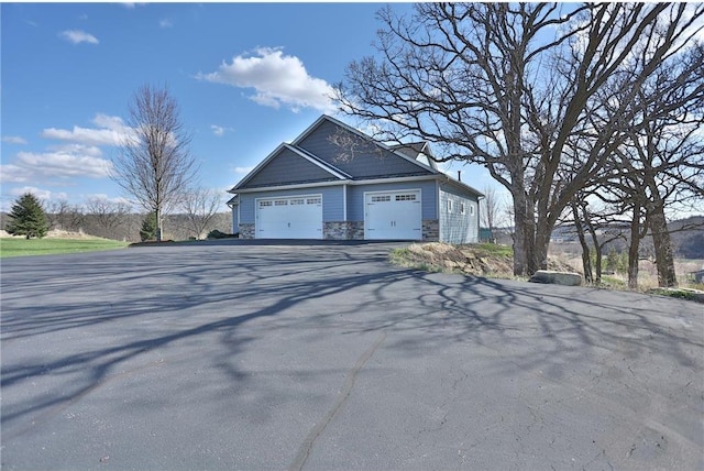 203 Walnut Hill Way, River Falls, WI 54022 - view of side of property featuring asphalt driveway, stone siding, and a garage