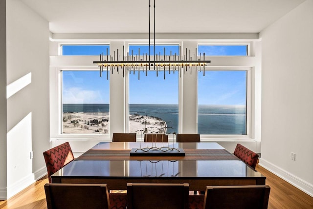 dining area featuring baseboards, a water view, and wood finished floors