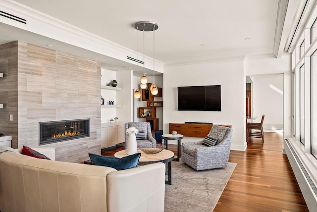 living area featuring visible vents, a tiled fireplace, a baseboard radiator, dark wood-style floors, and ornamental molding