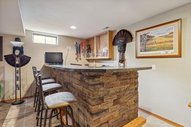 bar featuring wet bar, visible vents, baseboards, and tile patterned floors