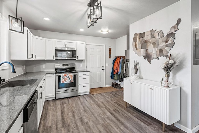 kitchen featuring baseboards, white cabinetry, a sink, dark wood finished floors, and appliances with stainless steel finishes