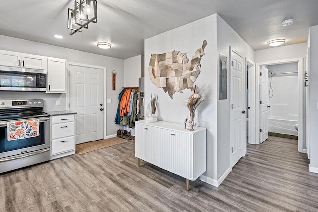 kitchen featuring baseboards, stainless steel appliances, light wood-type flooring, and white cabinetry