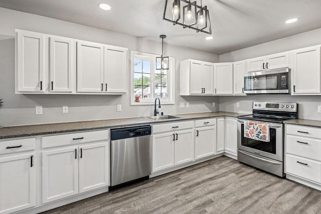 kitchen with recessed lighting, a sink, white cabinets, and stainless steel appliances