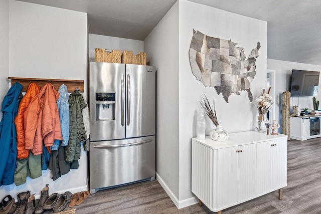 kitchen with light countertops, baseboards, stainless steel fridge, and wood finished floors