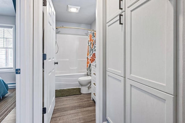 full bath with toilet, a baseboard heating unit, wood finished floors, and shower / tub combo