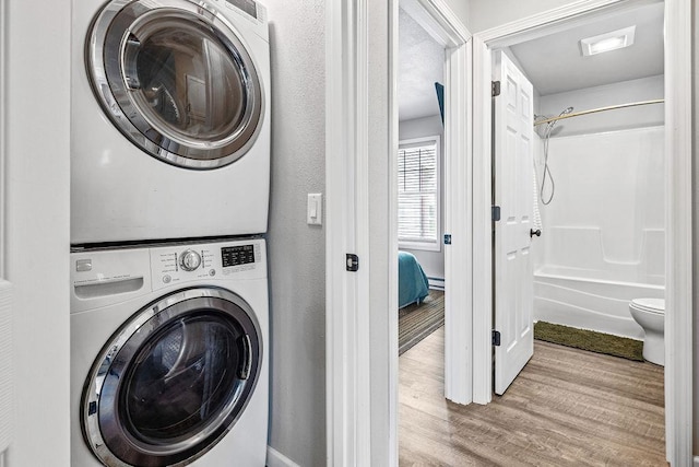 laundry area with stacked washing maching and dryer, laundry area, and wood finished floors