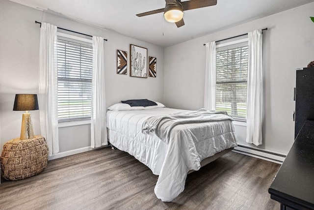 bedroom with a ceiling fan, baseboards, baseboard heating, and wood finished floors
