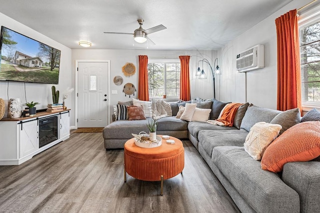 living room featuring a ceiling fan, an AC wall unit, and wood finished floors