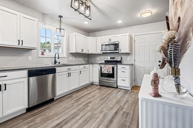 kitchen featuring a sink, light wood finished floors, appliances with stainless steel finishes, and white cabinets