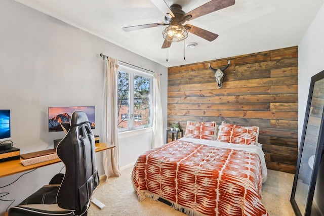carpeted bedroom with ceiling fan, wood walls, and baseboards