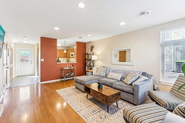 living area with recessed lighting, baseboards, and light wood-style flooring