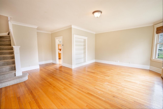 unfurnished living room featuring light wood-style floors, baseboards, ornamental molding, and stairs
