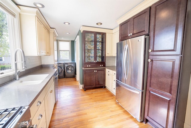 kitchen with stainless steel appliances, washing machine and dryer, a healthy amount of sunlight, and light wood-style flooring