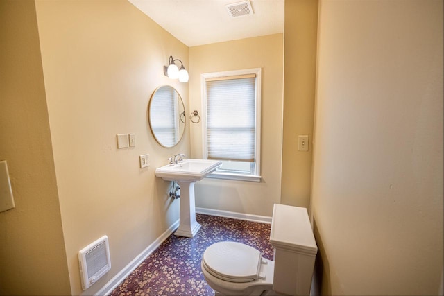 half bathroom featuring visible vents, baseboards, and toilet