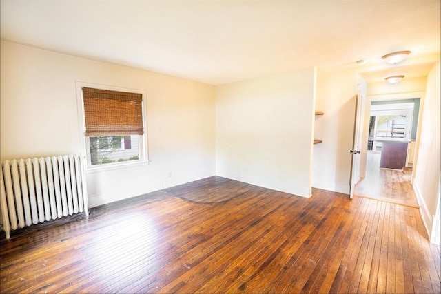 unfurnished room with radiator, baseboards, and wood-type flooring