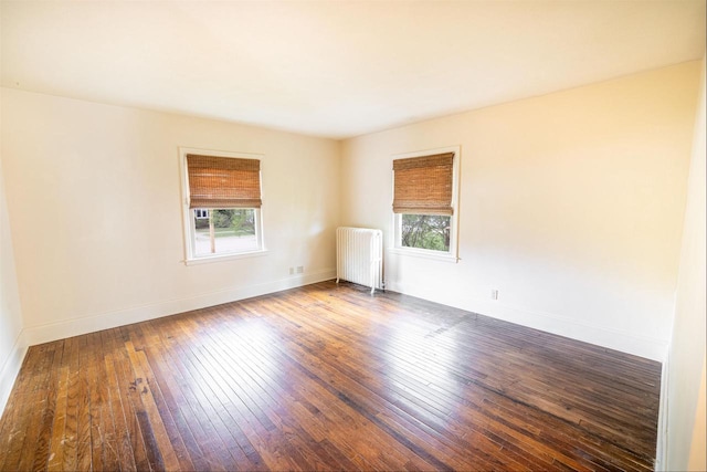 spare room with hardwood / wood-style flooring, plenty of natural light, baseboards, and radiator
