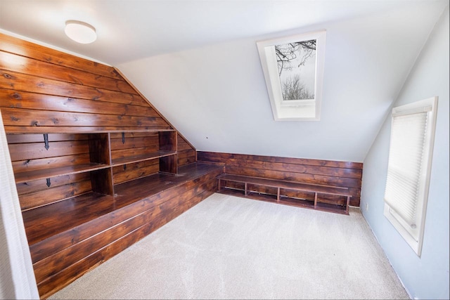 bonus room featuring carpet floors, wood walls, and lofted ceiling with skylight