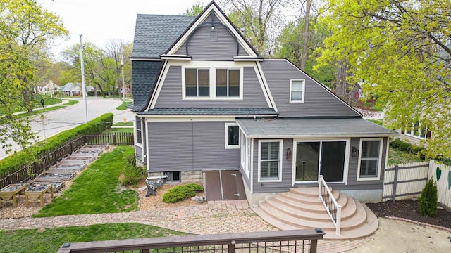 rear view of house featuring a shingled roof and a fenced backyard