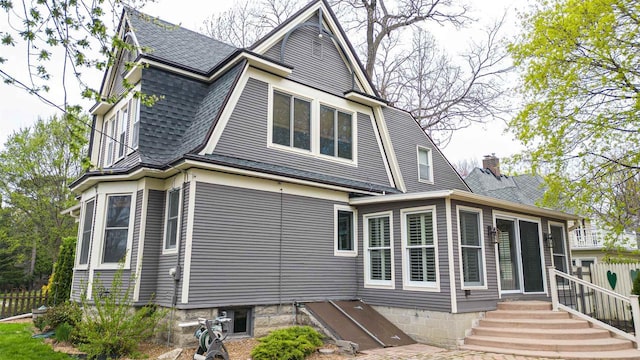 back of house with fence and a shingled roof
