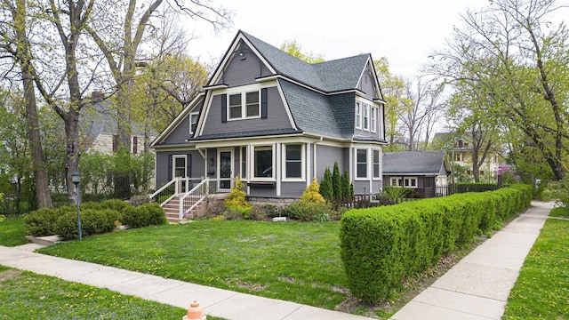 view of front of home featuring a shingled roof and a front yard