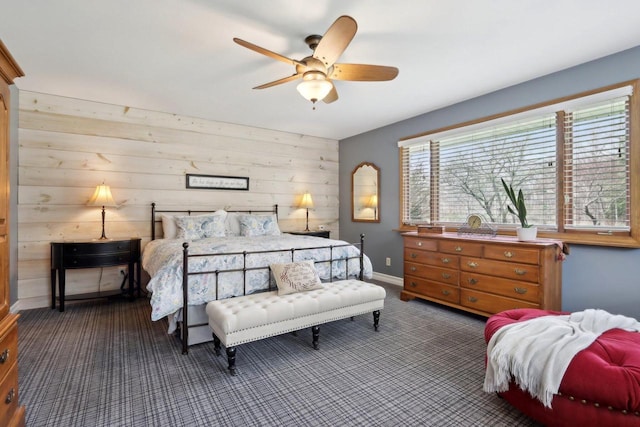 bedroom with baseboards, carpet flooring, a ceiling fan, and wooden walls