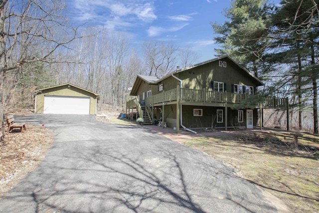 view of side of property featuring an outdoor structure, a wooden deck, stairway, and a detached garage