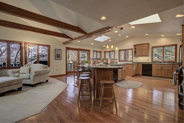 kitchen featuring dark countertops, a breakfast bar area, black dishwasher, recessed lighting, and lofted ceiling with skylight
