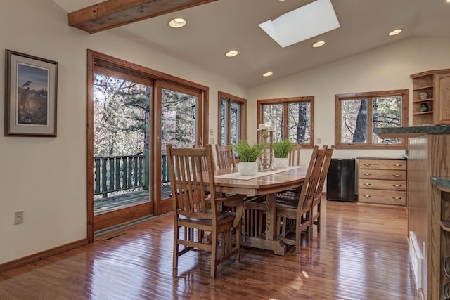 dining area with plenty of natural light, wood finished floors, and lofted ceiling with skylight