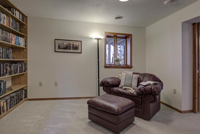 living area featuring baseboards, carpet, a textured ceiling, and visible vents