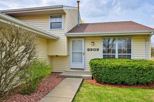 doorway to property featuring a shingled roof