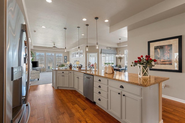 kitchen with light stone countertops, appliances with stainless steel finishes, dark wood finished floors, recessed lighting, and open floor plan