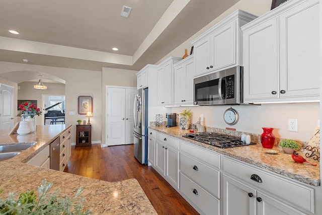 kitchen featuring arched walkways, dark wood-style floors, stainless steel appliances, recessed lighting, and white cabinetry