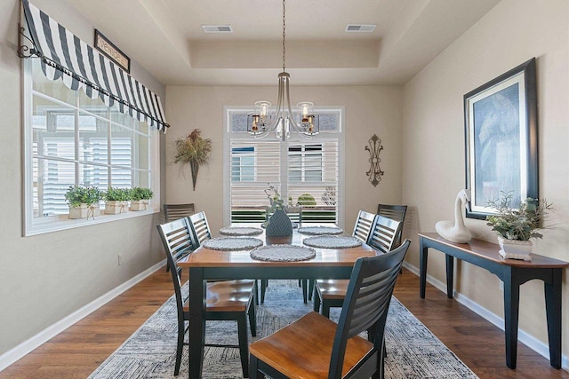 dining area featuring an inviting chandelier, a raised ceiling, visible vents, and a healthy amount of sunlight