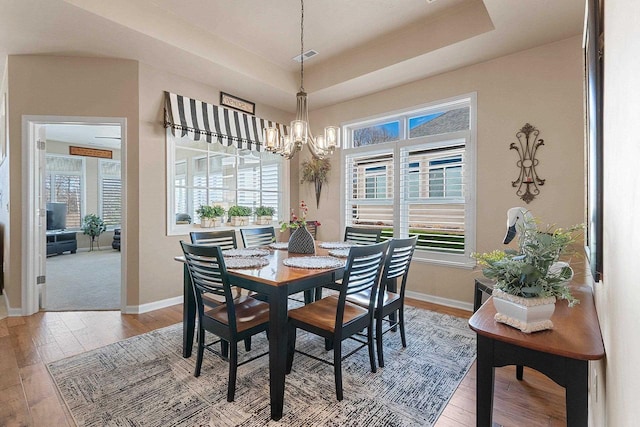 dining area with light wood-style floors, baseboards, a notable chandelier, and a wealth of natural light