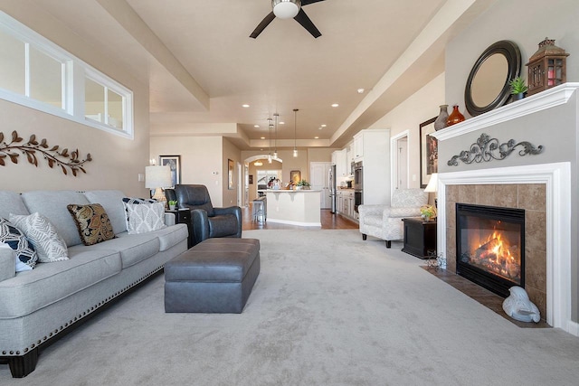 living room with a ceiling fan, light colored carpet, recessed lighting, and a tile fireplace