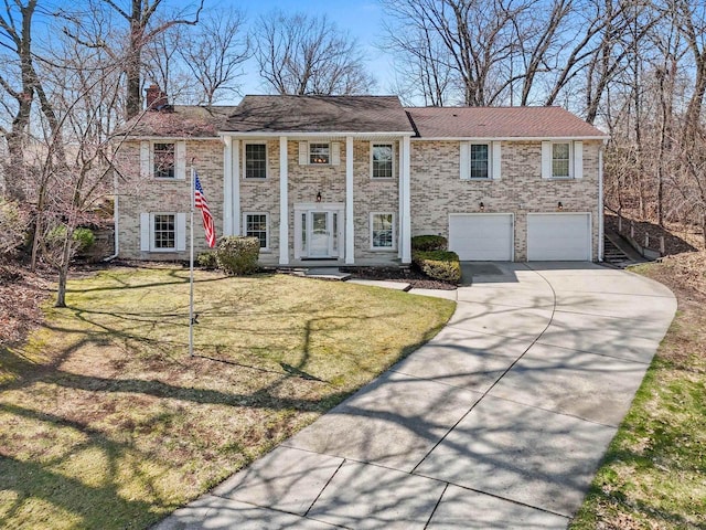 neoclassical home featuring concrete driveway, a chimney, a front yard, and a garage