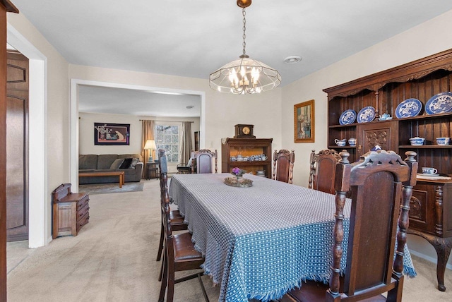 dining space featuring light carpet and a chandelier