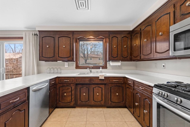 kitchen with light countertops, a sink, light tile patterned floors, and stainless steel appliances
