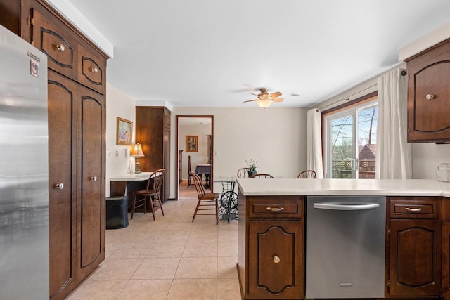 kitchen featuring light tile patterned flooring, ceiling fan, light countertops, stainless steel appliances, and a peninsula