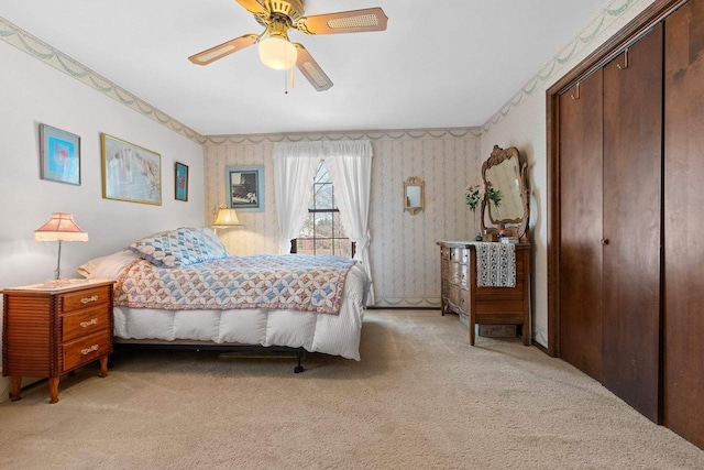 bedroom featuring wallpapered walls, light colored carpet, ceiling fan, and a closet