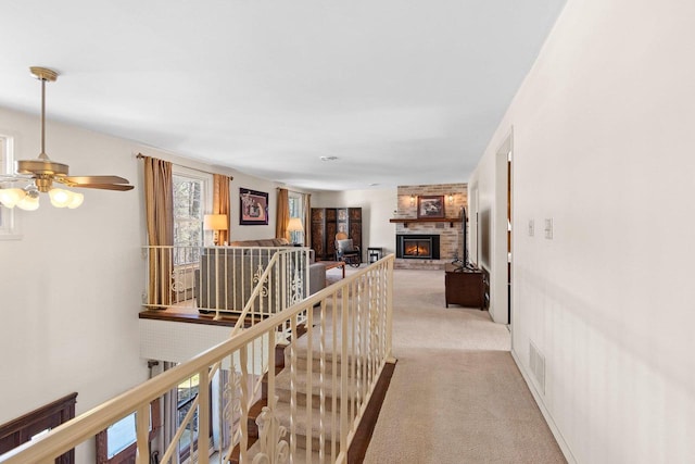 corridor featuring carpet floors, visible vents, and an upstairs landing