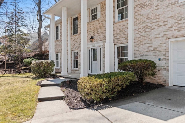 doorway to property with brick siding and a garage